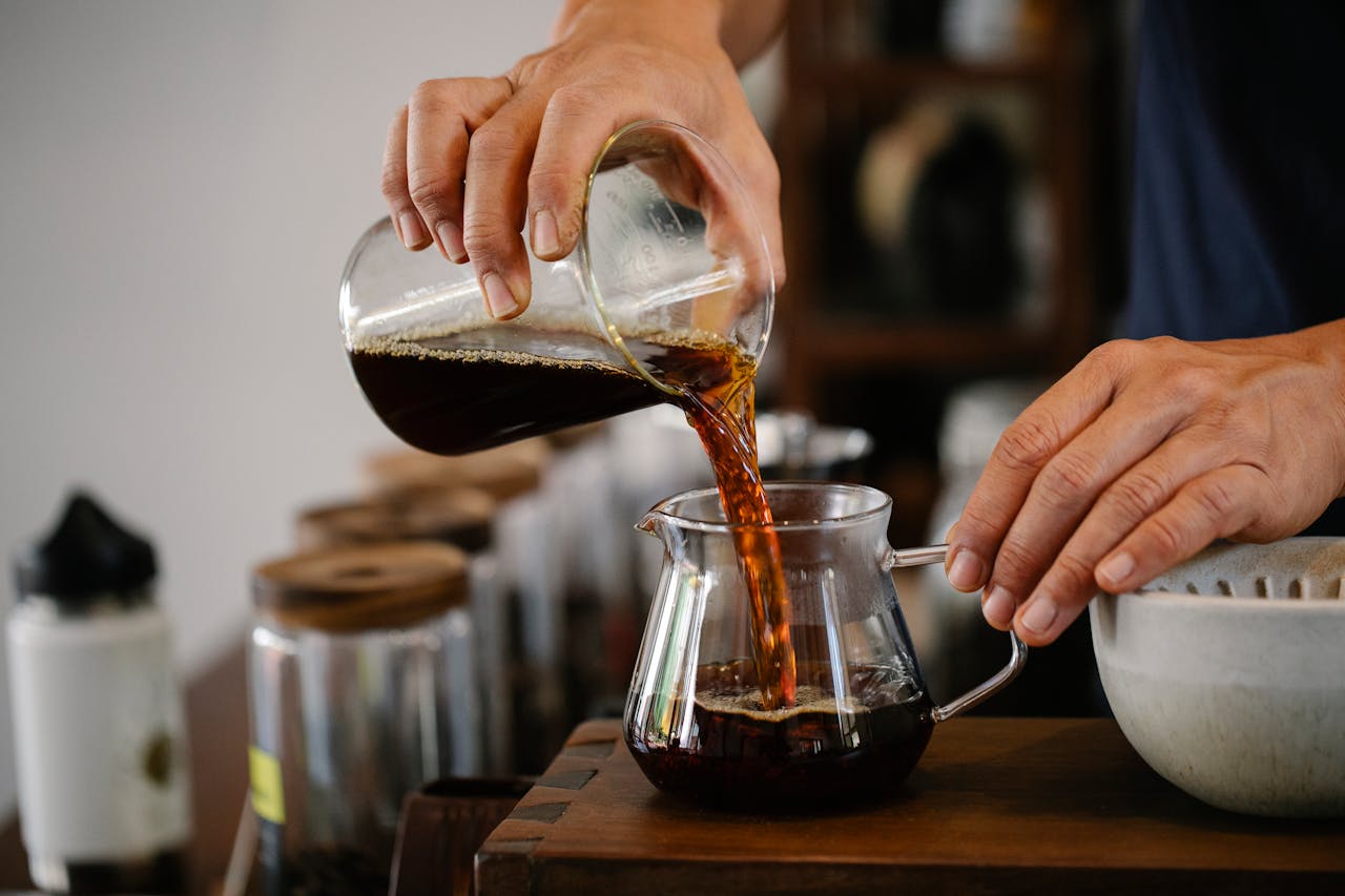 Güneşli bir mutfakta, buharı tüten cam bir French Press ile hazırlanmış dolgun gövdeli kahve